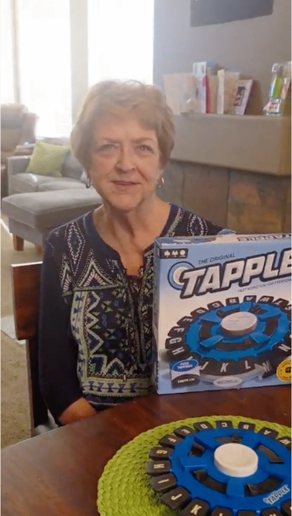 Grandmother holding the Tapple word game during family game night at home