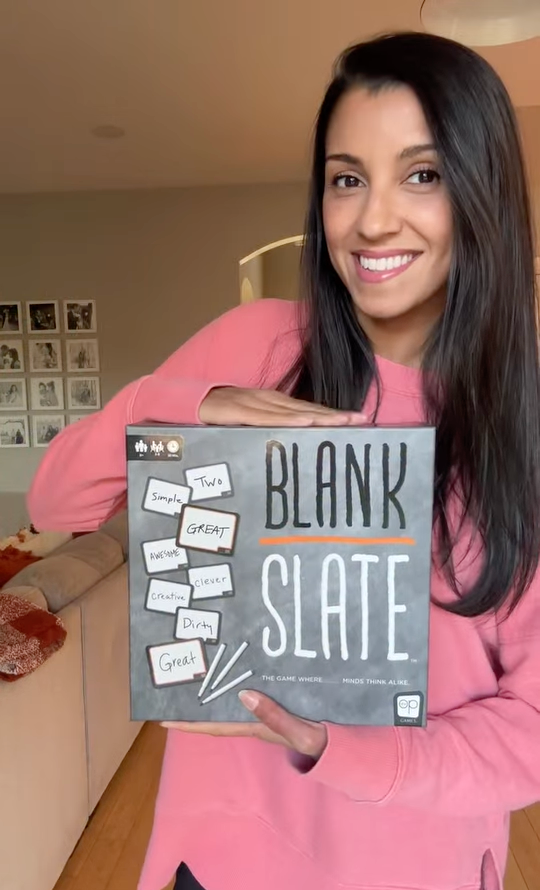 Woman holding the Blank Slate word association game during family game night