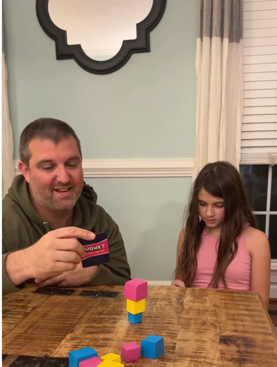 Players stacking blocks while playing the Wonky unstable party game at a table.