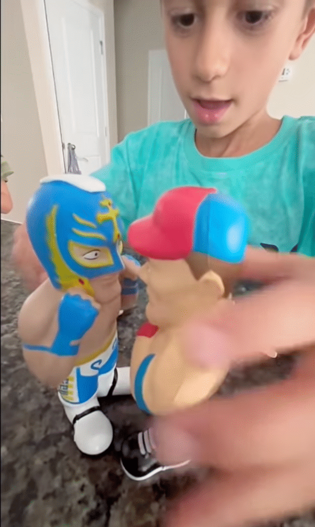 Child playing with WWE Smash N Squish collectible figures, pressing two WWE characters together during interactive play